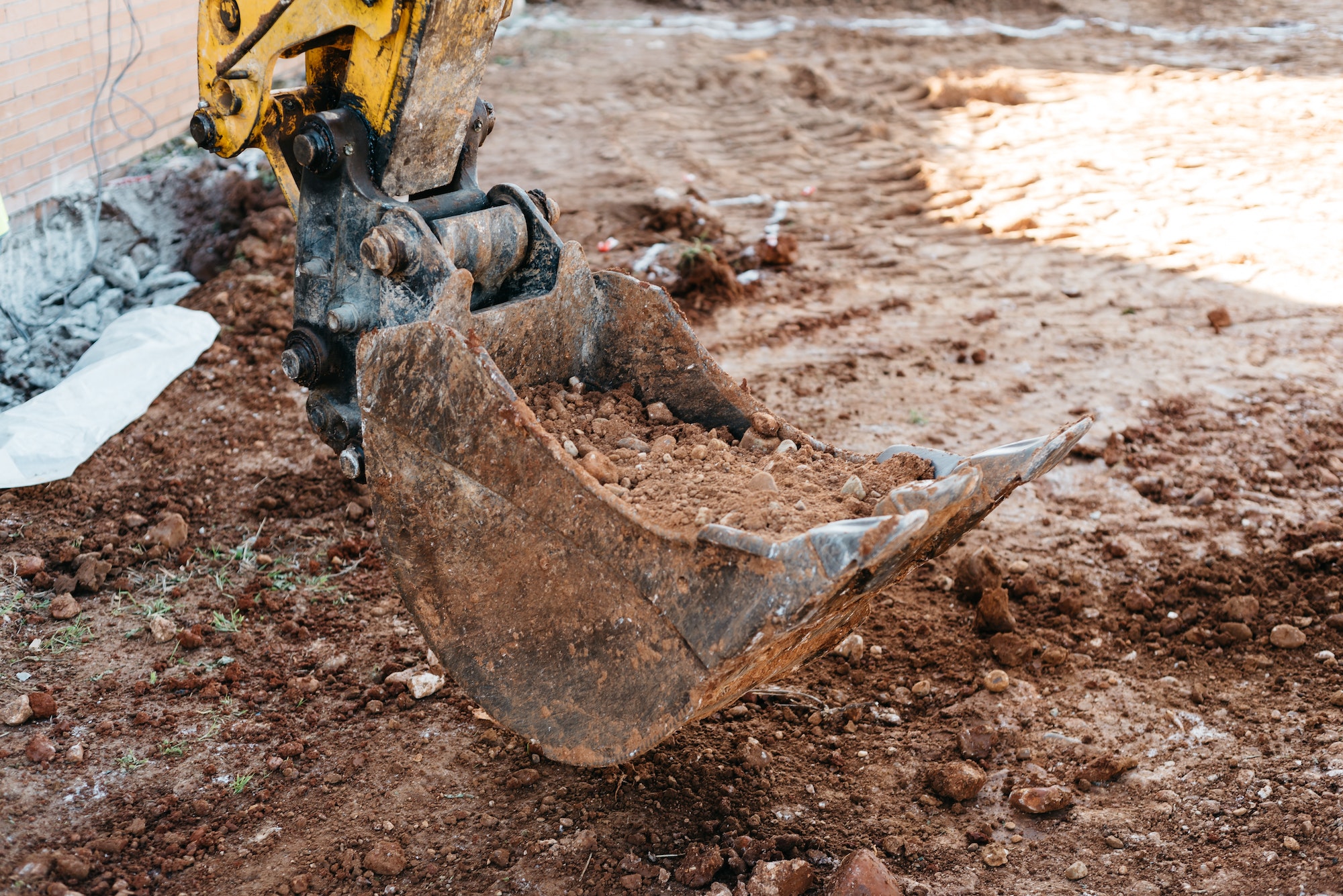 Shovel machine on construction site with worker working with pneumatic hammer on background